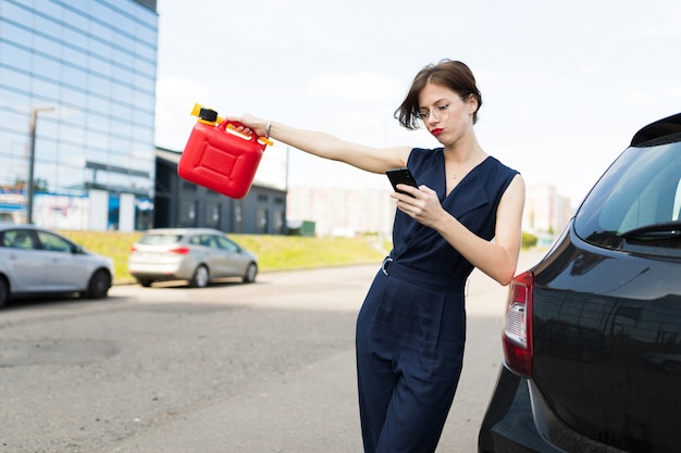 Mooie zakenvrouw met behulp van mobiele telefoon naast de auto