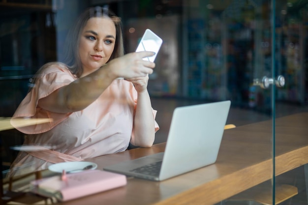 Mooie zakenvrouw met een grote maat die zich voordeed met het nemen van selfies, gebruik een smartphone die op afstand werkt in café