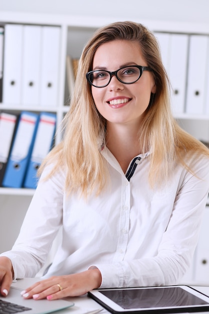 Mooie zakenvrouw portret in het kantoor zit aan de tafel