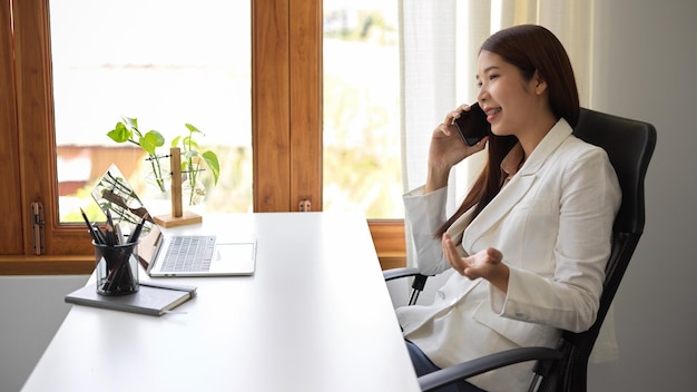 Mooie zakenvrouw praten aan de telefoon op haar moderne bureau werkruimte zijaanzicht