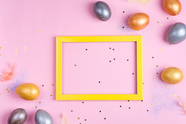 Mooie zilveren en gouden eieren van Pasen met geel kader op roze sterrenachtergrond
