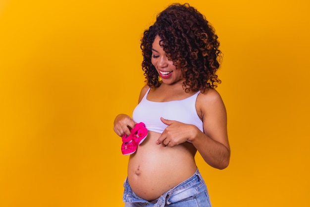 Mooie zwangere moeder met roze pantoffel op gele achtergrond