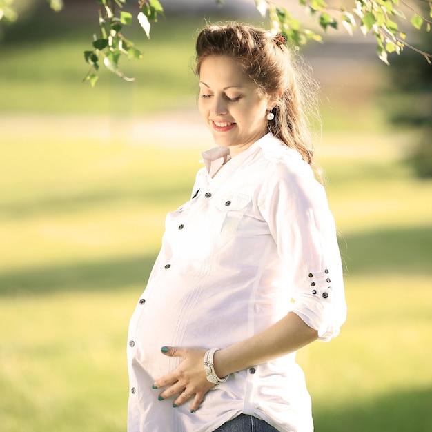 Mooie zwangere vrouw die buiten in het park ontspant