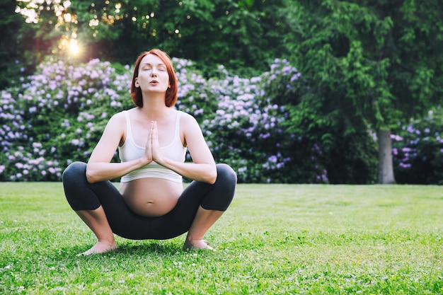 Mooie zwangere vrouw die prenatale yoga doet op de natuur in de buitenlucht Zwangere vrouw die yoga beoefent