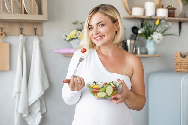 Foto mooie zwangere vrouw die salade eet