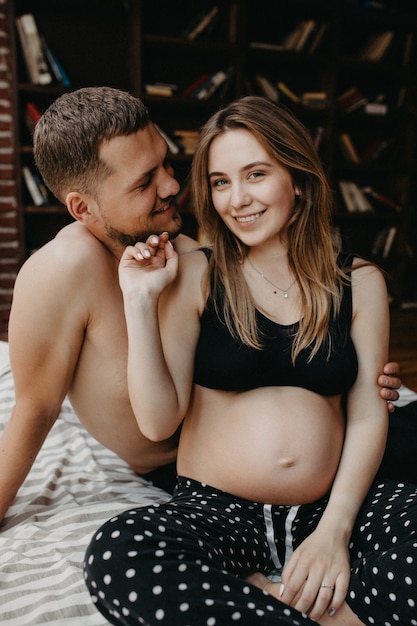 Mooie zwangere vrouw en haar knappe echtgenoot knuffelen en glimlachen terwijl ze samen tijd doorbrengen