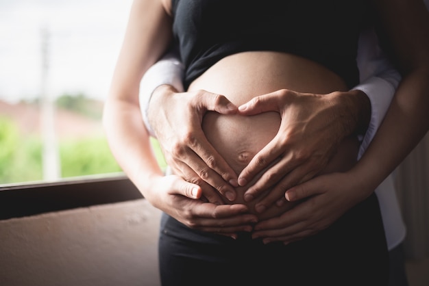 Mooie zwangere vrouw en haar knappe man knuffelen de buik