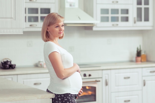 Mooie zwangere vrouw in witte binnenlandse keuken