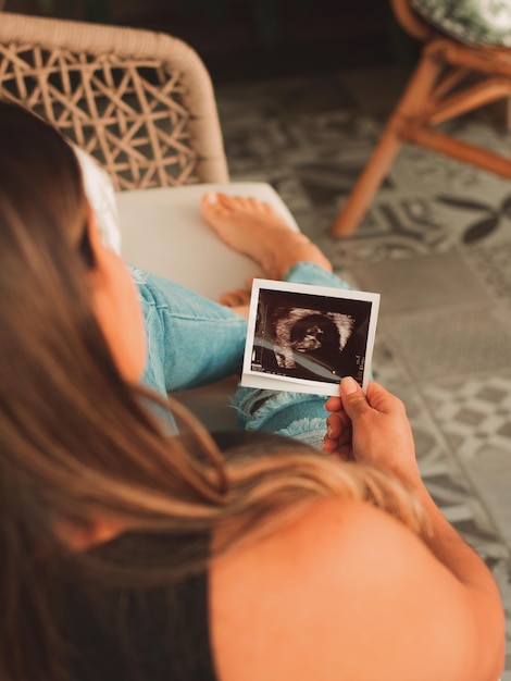 Mooie zwangere vrouw kijkt naar de echo van haar baby