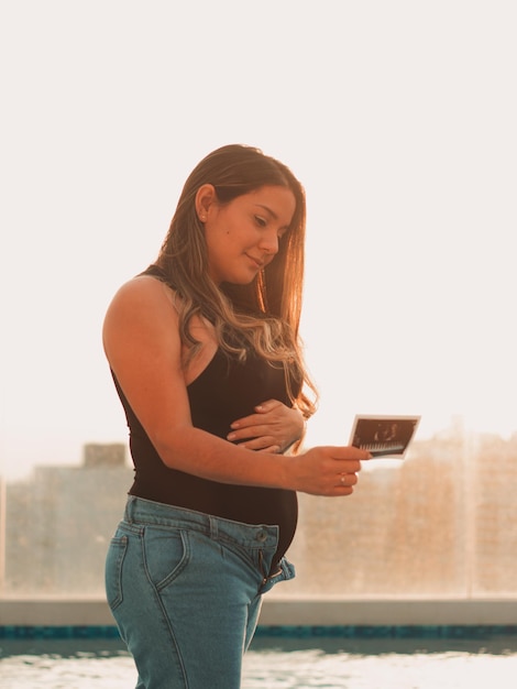 Mooie zwangere vrouw kijkt naar de echo van haar baby