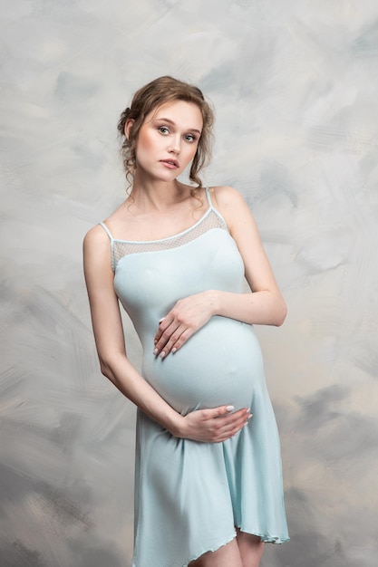 Mooie zwangere vrouw met bloemen op buik Jonge vrouw in moederschap die op babygeboorte wacht Zwangerschap Moederschap Moederdag Vakantieconcept