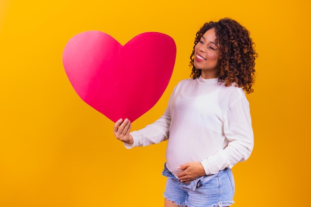 Mooie zwangere vrouw met een hartvormige kaart met vrije ruimte voor tekst