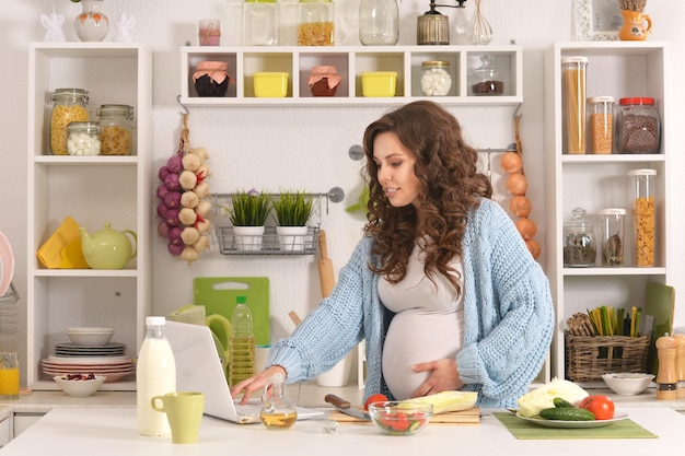 Mooie zwangere vrouw met eten in de keuken