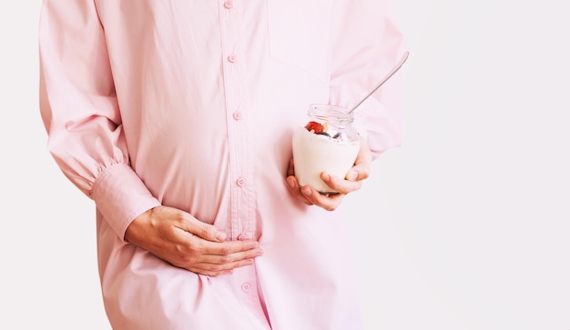 Mooie zwangere vrouw met gezonde snack van yoghurt met muesli en fruit Voeding tijdens de zwangerschap Concept dieet en gezondheid aanstaande moeder en haar baby