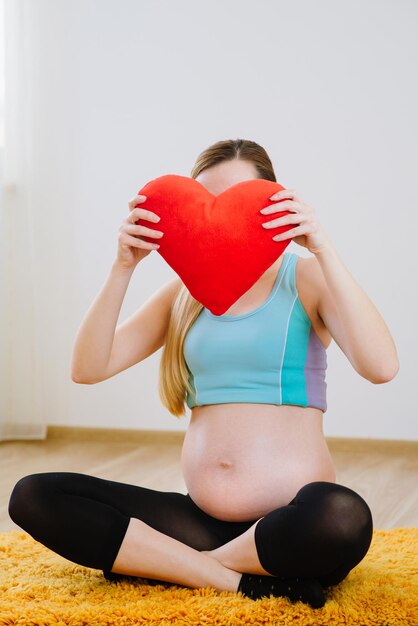 Mooie zwangere vrouw met kussen in hartvorm