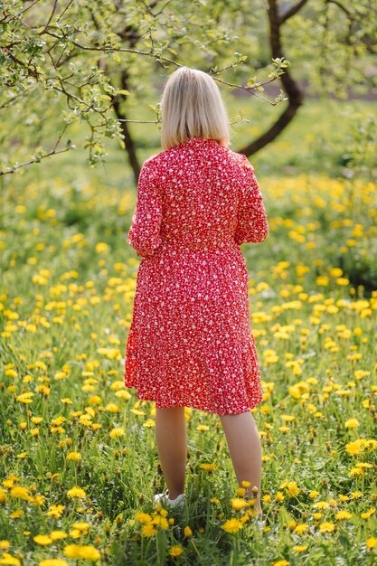 Mooie zwangere vrouw ontspannen in het park, gekleed in rode jurk