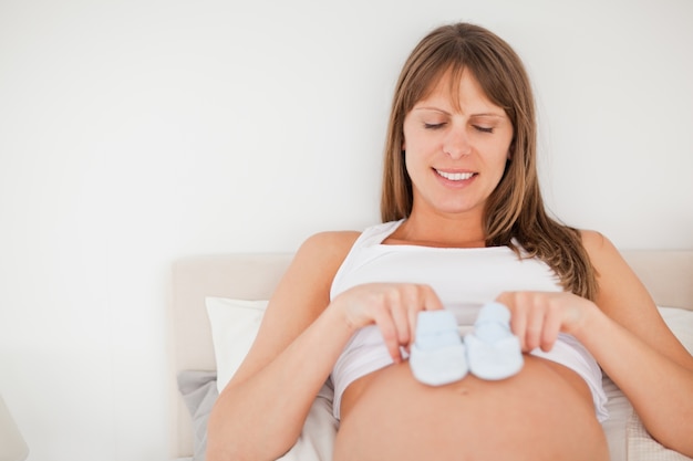 Mooie zwangere vrouw spelen met kleine sokken liggend op een bed