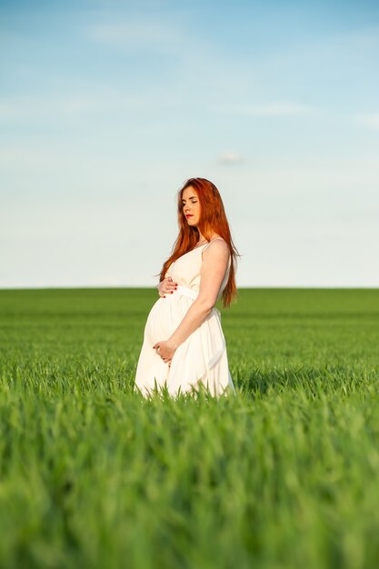 Mooie zwangere vrouw zomer portret wandelen op groen veld