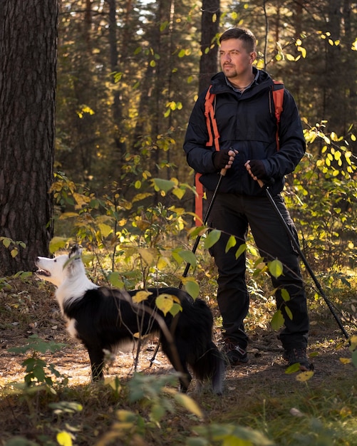 Foto mooie zwart-witte hond en man in het bos