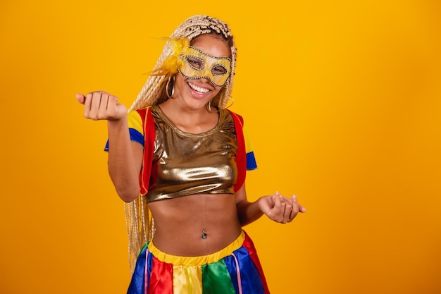 Mooie zwarte Braziliaanse vrouw gekleed in carnaval kleding masker gele achtergrond komt uitnodigend met je handen