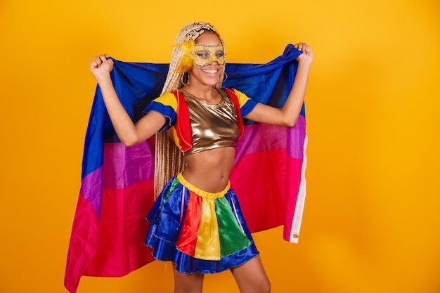 Mooie zwarte Braziliaanse vrouw gekleed in carnaval kleding masker gele achtergrond met biseksuele vlag