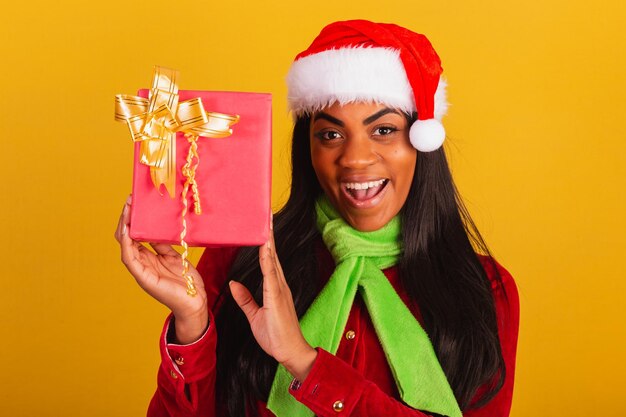 Mooie zwarte Braziliaanse vrouw gekleed in kerstkleding kerstman close-up foto met rode cadeau