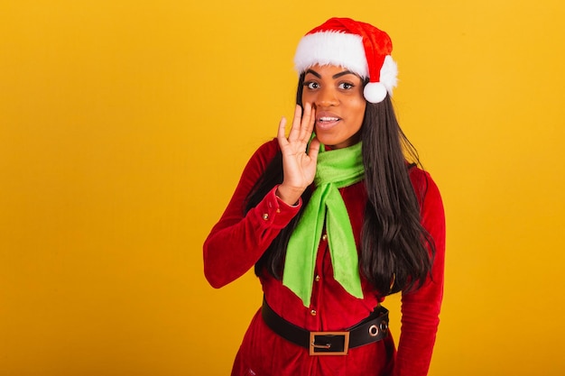 Mooie zwarte braziliaanse vrouw gekleed in kerstkleding santa claus geheim vertellen