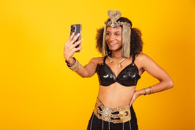 Mooie zwarte Braziliaanse vrouw in Cleopatra-carnavalkleren die zelfportret met smartphone maken
