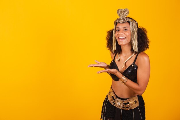 Mooie zwarte Braziliaanse vrouw in Cleopatra-carnavalskleding die iets naar links presenteert