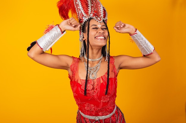 Mooie zwarte Braziliaanse vrouw met rode carnavalskleding die zich heel gelukkig uitstrekt