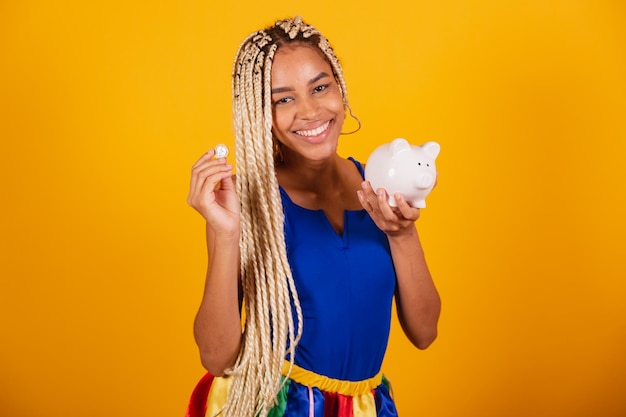 Mooie zwarte braziliaanse vrouw met vlechten die kleding dragen voor carnaval Holding munt en spaarvarken