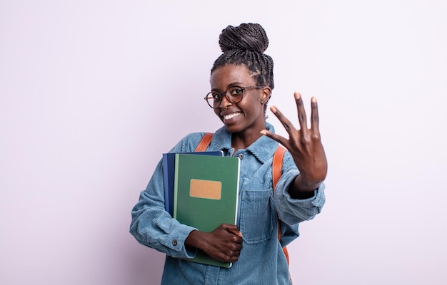 Mooie zwarte vrouw die lacht en er vriendelijk uitziet, met nummer vier. student met boeken concept