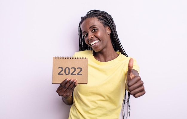Mooie zwarte vrouw die trots positief glimlacht met duimen omhoog 2022 kalenderconcept
