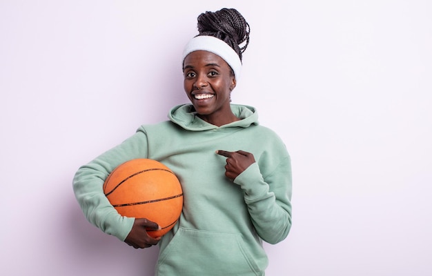 Mooie zwarte vrouw die zich gelukkig voelt en naar zichzelf wijst met een opgewonden basketbal concept