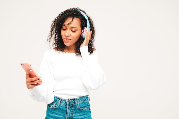 Mooie zwarte vrouw met afro krullen kapsel. Glimlachend model in trui en jeans