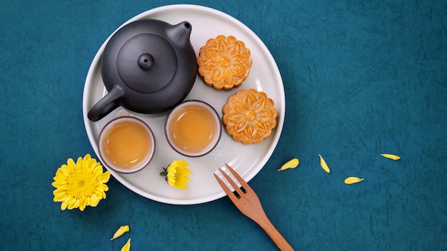 Moon cake for midautumn festival delicious beautiful fresh\
mooncake on a plate over blue background table top view flat lay\
layout design concept