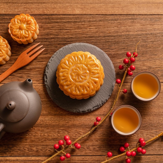 Фото Лунный пирог лунный пирог сервировка стола китайская традиционная выпечка с чайными чашками на деревянном фоне концепция фестиваля середины осени, вид сверху, плоская планировка