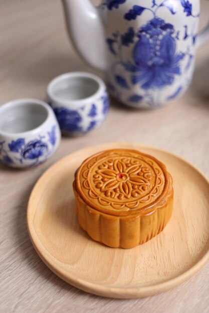 写真 木製の皿の月のケーキと木製の背景の中国茶碗