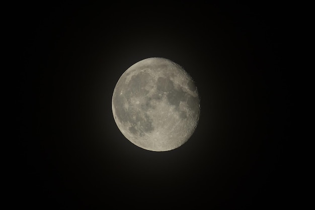 Photo the moon is visible through the clouds in the dark sky.