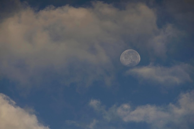 月とそれは朝の青い空の雲の上のクレーターです