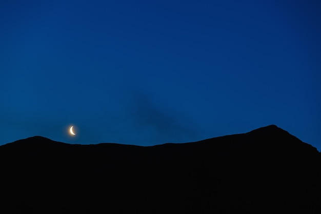 山の尾根の上の夜空の月