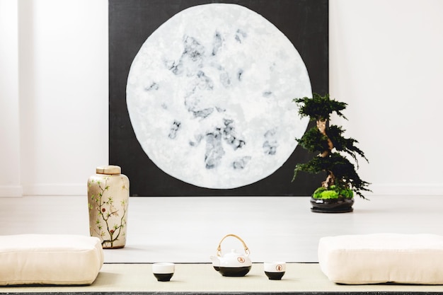 Photo moon poster and bonsai between pillows on the floor in japanese dining room interior real photo with blurred background