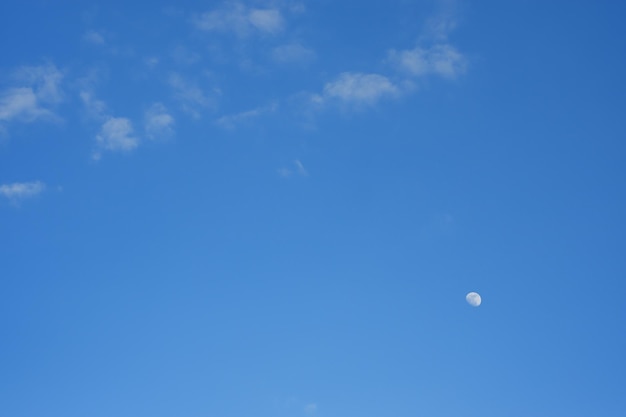 Луна сияет в дневное время посреди неба, ярко окрашенного серфингом в Таиланде.