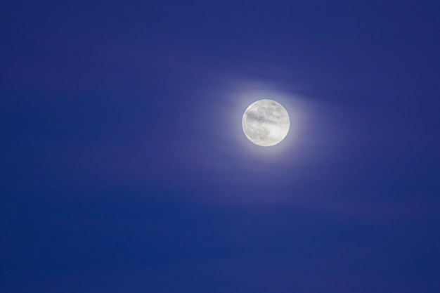 青い時間の間に空に柔らかい雲を持つ月