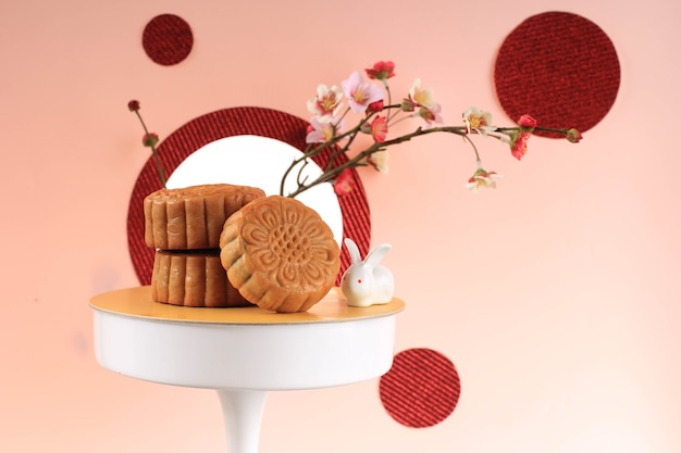 Foto mooncake su sfondo rosa chiaro con fiore rosa. torta della luna di concetto sul festival di metà autunno. mooncake popolare come kue bulan.