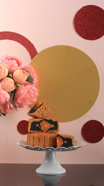 Mooncake on Light Pink Background with Pink Flower. Concept Moon Cake on Mid Autumn Festival. Mooncake Popular as Kue Bulan.