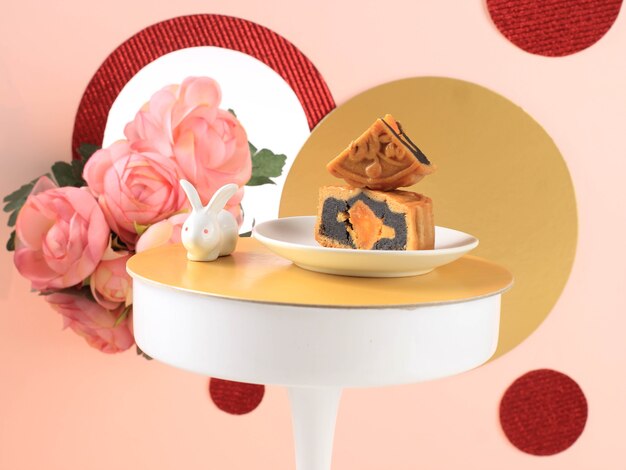 Foto mooncake su sfondo rosa chiaro con fiore rosa. torta della luna di concetto sul festival di metà autunno. mooncake popolare come kue bulan.