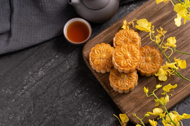 Mooncake moon cake voor midautumn festival concept van traditionele feestelijke gerechten op zwarte leisteen tafel met thee en gele bloem close-up kopie ruimte