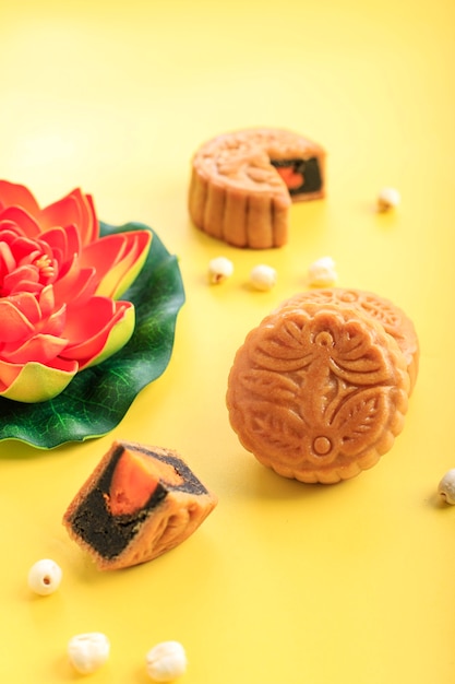 Mooncake op lichtgele achtergrond met oranje lotusbloem. Concept Moon Cake op Mid Autumn Festival. Mooncake populair als Kue Bulan.