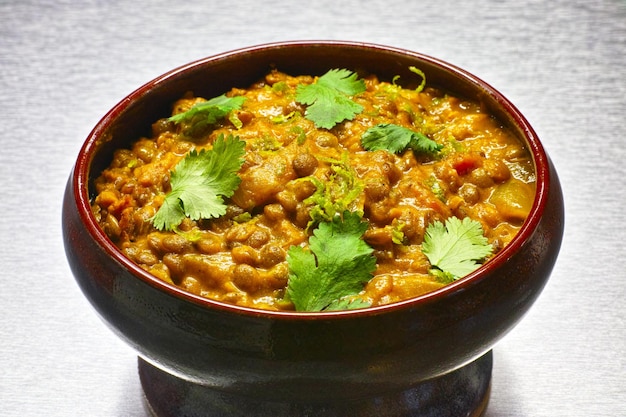 Moong Dal indian vegetarian lentil soup in terra cotta bowl Aluminium background